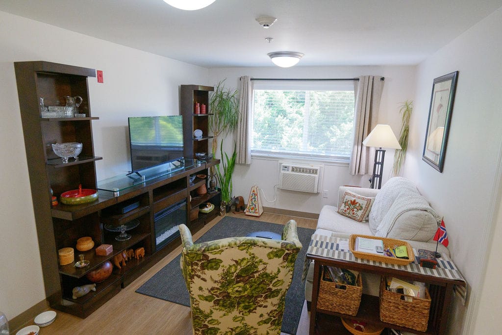 Resident apartment living room at McLoughlin Place with a television, a sofa, framed pictures and personal belongings