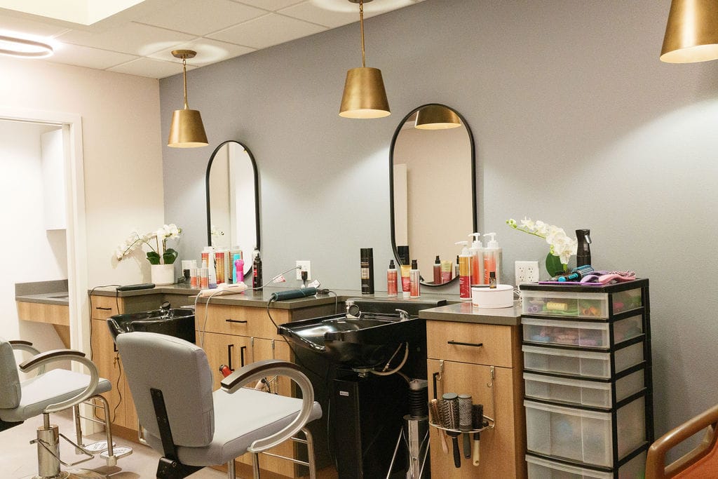 Salon with two styling stations, arched mirrors and brass pendant lights